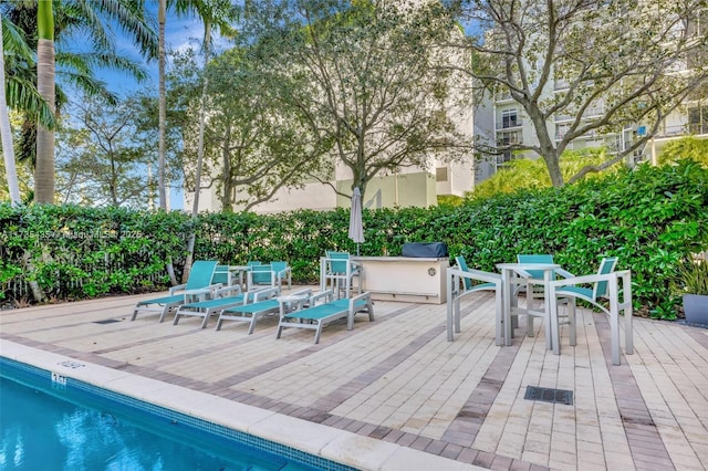 wooden terrace with an outdoor kitchen and a community pool