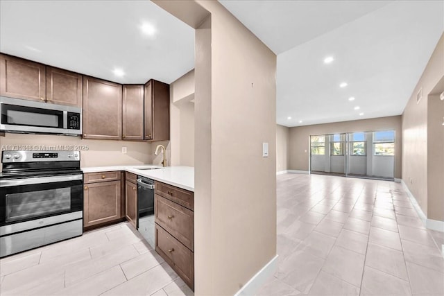 kitchen with sink, light tile patterned floors, dark brown cabinets, and appliances with stainless steel finishes