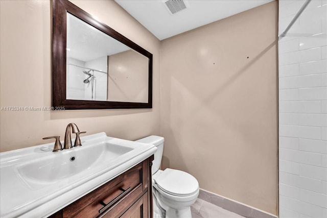 bathroom with vanity, a tile shower, tile patterned floors, and toilet