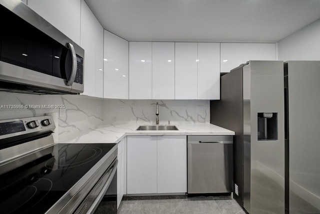 kitchen featuring sink, tasteful backsplash, appliances with stainless steel finishes, light stone countertops, and white cabinets