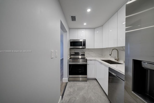 kitchen with white cabinetry, sink, backsplash, and appliances with stainless steel finishes