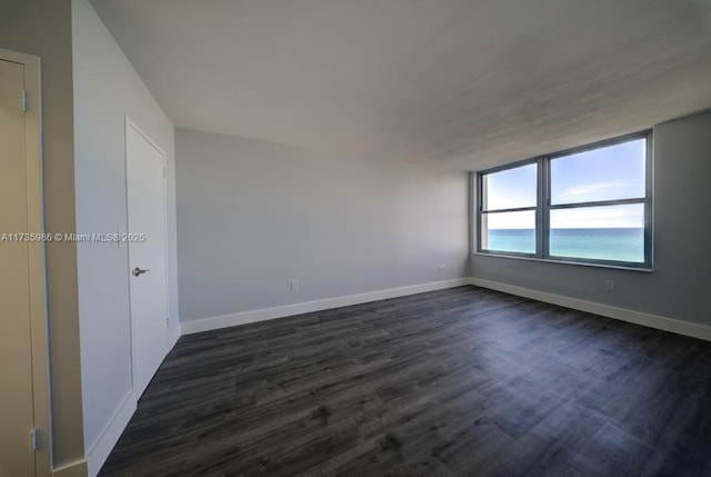 unfurnished room with dark hardwood / wood-style floors and a water view