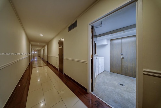 corridor with washing machine and clothes dryer and tile patterned floors