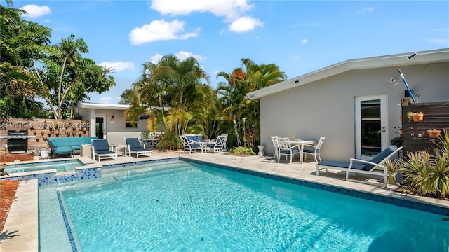 view of pool featuring grilling area, outdoor dining space, a pool with connected hot tub, and a patio