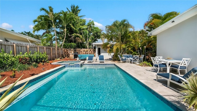 view of swimming pool featuring fence, a pool with connected hot tub, outdoor dining space, and a patio area