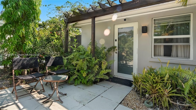 doorway to property featuring a patio, a pergola, and stucco siding