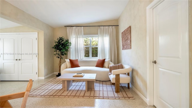 living area with baseboards, speckled floor, and lofted ceiling