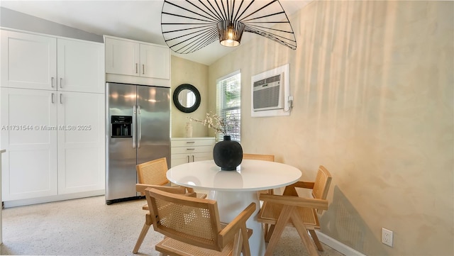 dining room with baseboards, light speckled floor, and a wall unit AC