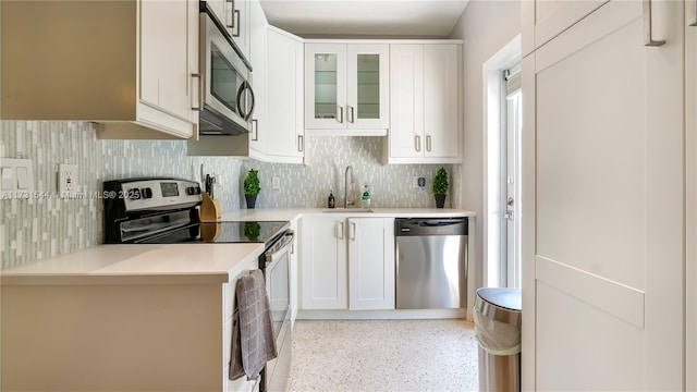 kitchen with a sink, decorative backsplash, light countertops, appliances with stainless steel finishes, and white cabinetry