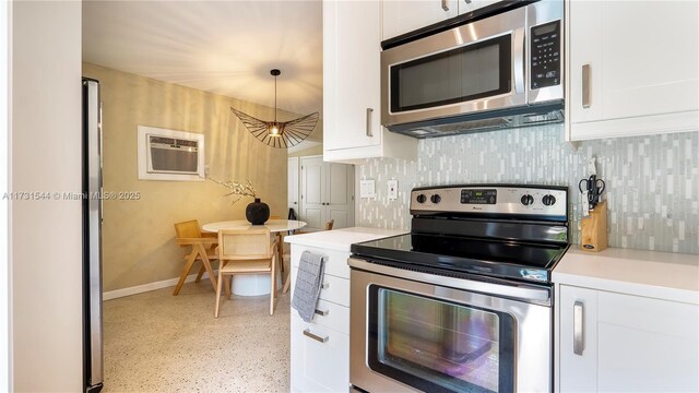 kitchen featuring stainless steel appliances, hanging light fixtures, a wall mounted air conditioner, and white cabinets