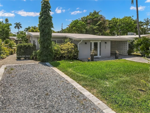 view of front of property with stucco siding, french doors, and a front yard