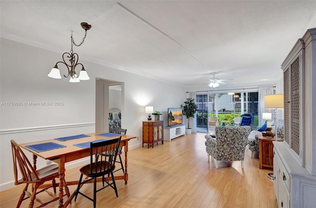 dining space with crown molding, ceiling fan with notable chandelier, and light wood-type flooring