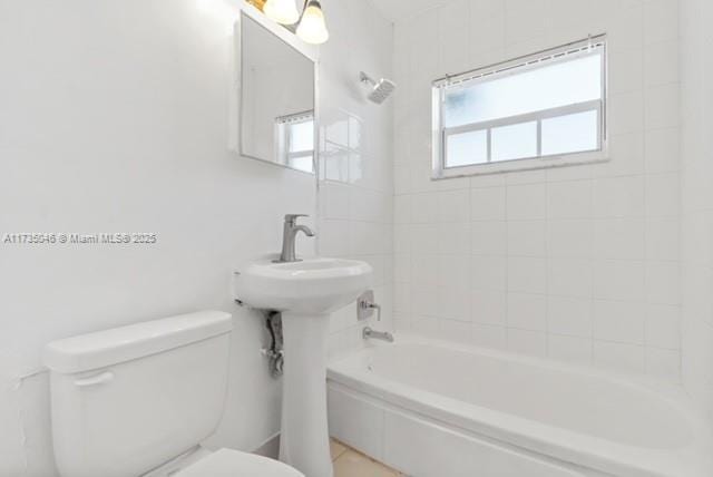 bathroom featuring tiled shower / bath combo and toilet