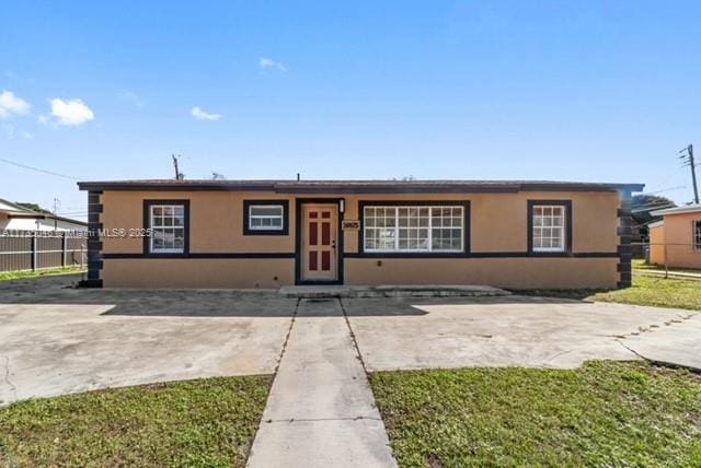 ranch-style home featuring a front lawn and a patio