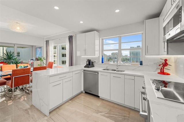 kitchen featuring appliances with stainless steel finishes, sink, white cabinets, and kitchen peninsula