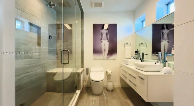 bathroom featuring vanity, a shower with shower door, hardwood / wood-style floors, and toilet