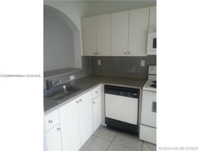 kitchen with white appliances, light tile patterned floors, sink, white cabinets, and decorative backsplash