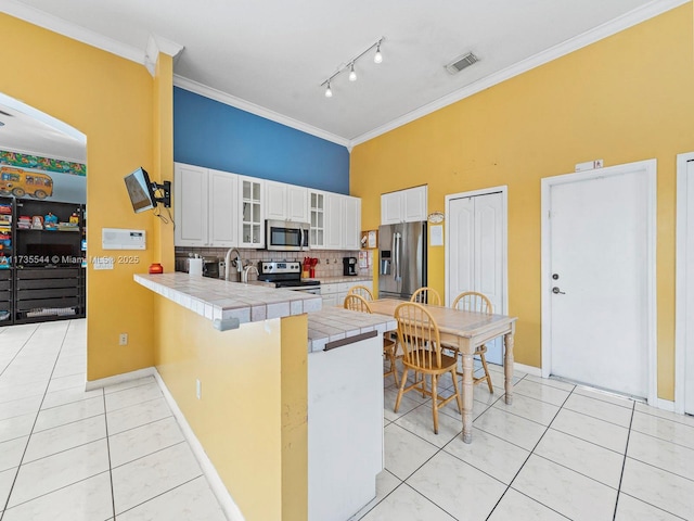 15804 SW 99th Ter, Miami, FL 33196 - kitchen with stainless steel appliances, a peninsula, light tile patterned flooring, tile countertops, and tasteful backsplash