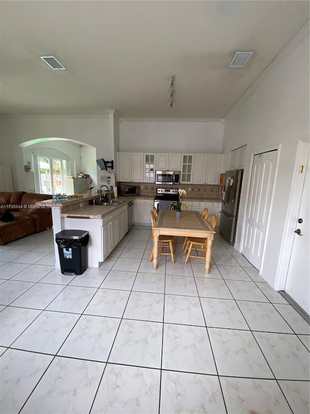 15804 SW 99th Ter, Miami, FL 33196 - kitchen featuring appliances with stainless steel finishes, a peninsula, open floor plan, tasteful backsplash, and crown molding