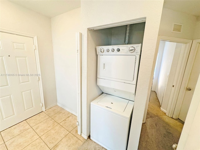 laundry area featuring stacked washer / drying machine and light tile patterned floors