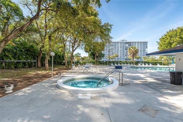 view of swimming pool featuring a hot tub and a patio