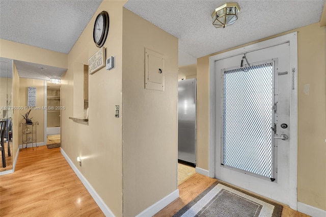 interior space with a textured ceiling, light wood-type flooring, and electric panel