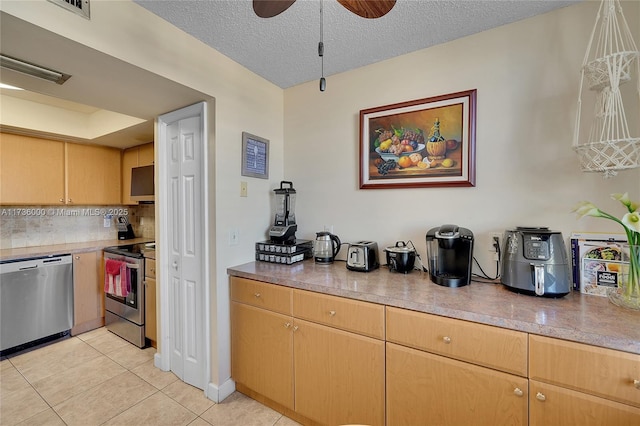 kitchen with light tile patterned floors, ceiling fan, stainless steel appliances, tasteful backsplash, and a textured ceiling