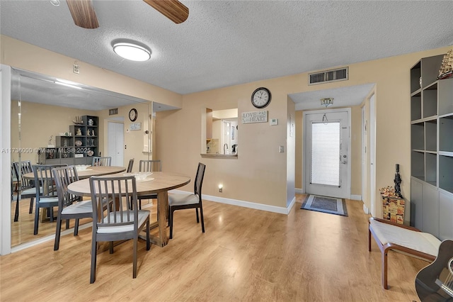 dining space with ceiling fan, light hardwood / wood-style floors, and a textured ceiling