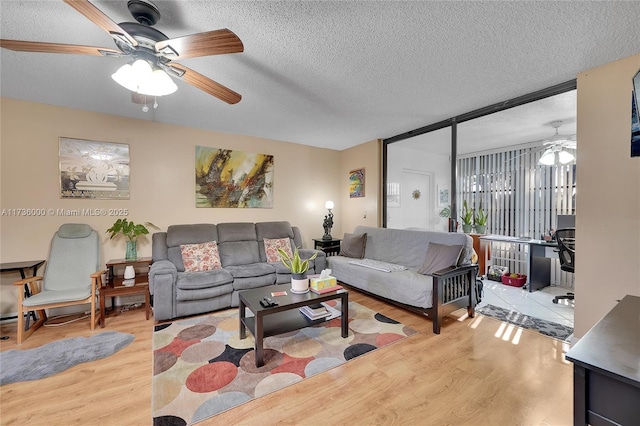 living room featuring ceiling fan, a textured ceiling, and light hardwood / wood-style floors