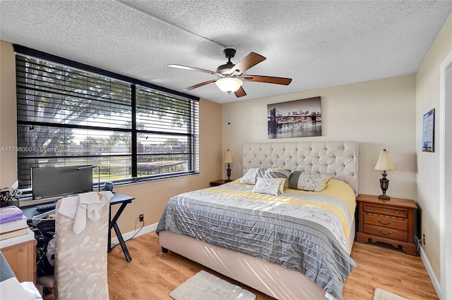 bedroom with ceiling fan, light hardwood / wood-style flooring, and a textured ceiling