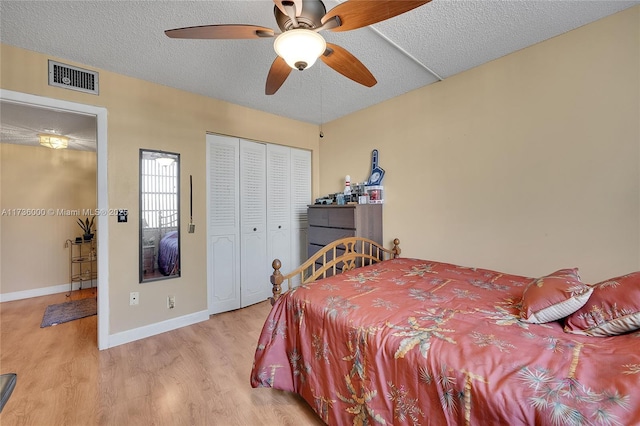 bedroom with ceiling fan, a closet, light hardwood / wood-style flooring, and a textured ceiling