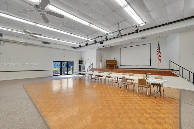 interior space with a paneled ceiling, parquet floors, a high ceiling, ceiling fan, and track lighting