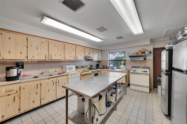 kitchen with appliances with stainless steel finishes, light brown cabinetry, and sink