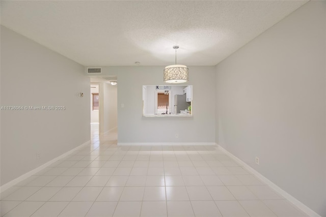 spare room with light tile patterned floors and a textured ceiling