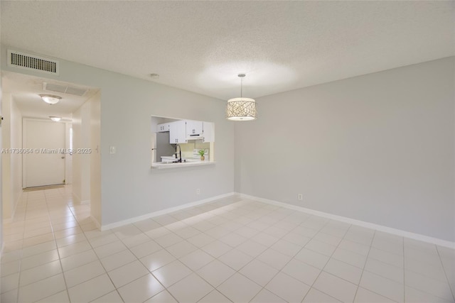 spare room featuring sink, light tile patterned floors, and a textured ceiling