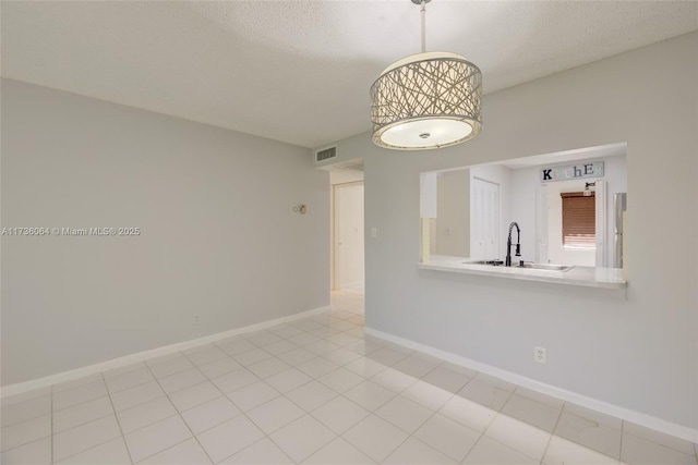 tiled empty room with sink and a textured ceiling