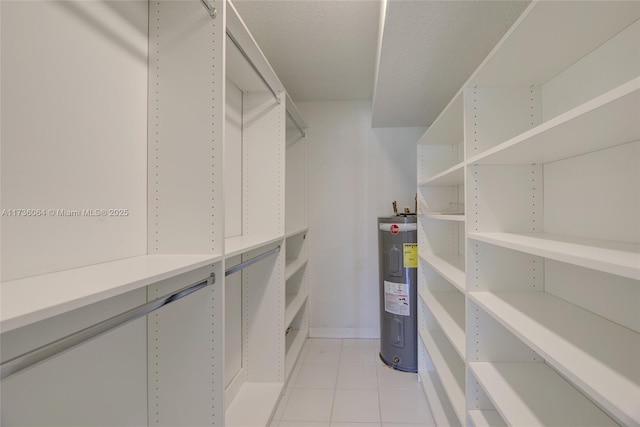 spacious closet featuring electric water heater and light tile patterned floors