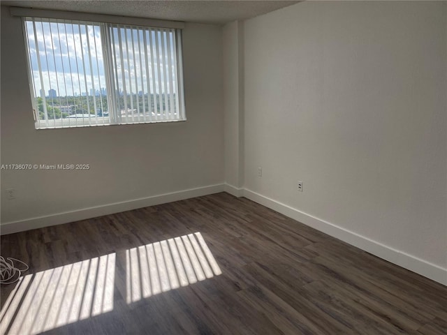 spare room featuring dark hardwood / wood-style floors and a textured ceiling