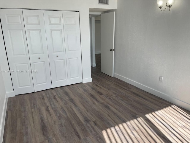 unfurnished bedroom with dark hardwood / wood-style floors and a closet