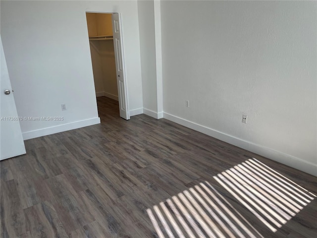 unfurnished bedroom featuring dark hardwood / wood-style flooring, a walk in closet, and a closet