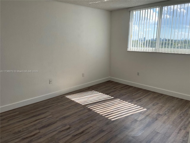 empty room with dark wood-type flooring and a textured ceiling