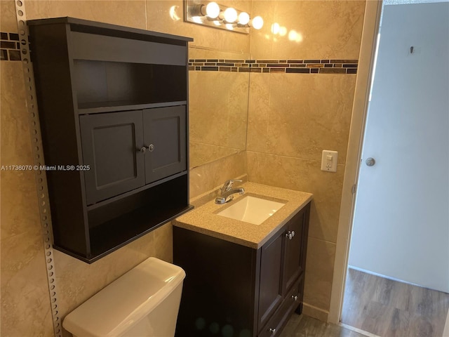 bathroom featuring tile walls, vanity, and toilet