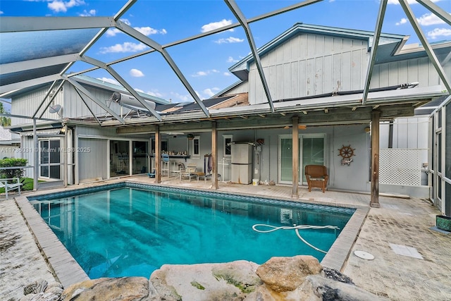 pool featuring glass enclosure, a patio area, and a ceiling fan