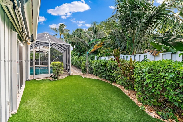 view of yard featuring glass enclosure, an outdoor pool, and a fenced backyard