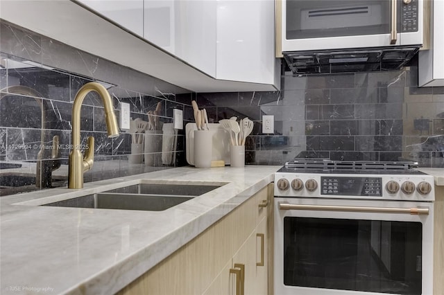 kitchen featuring tasteful backsplash, appliances with stainless steel finishes, sink, and light stone counters