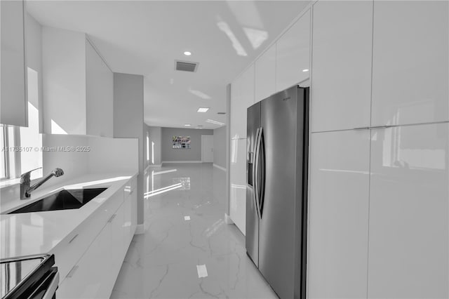 kitchen featuring white cabinetry, sink, stainless steel fridge, and range with electric cooktop