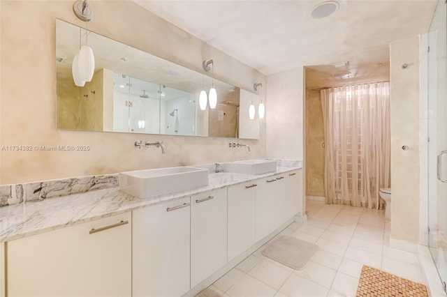 bathroom featuring tile patterned flooring, vanity, a shower with shower door, and toilet