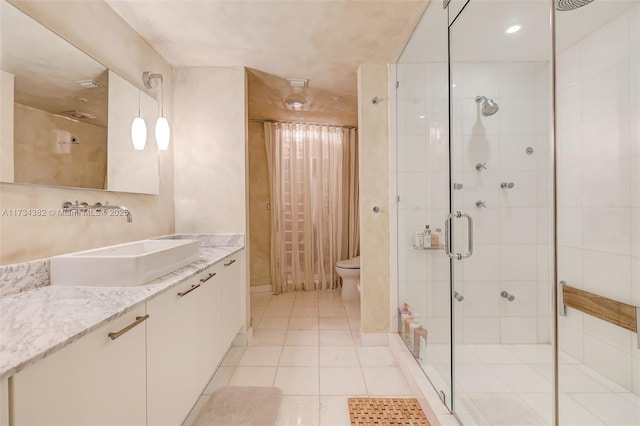 bathroom with tile patterned flooring, vanity, a shower with shower door, and toilet