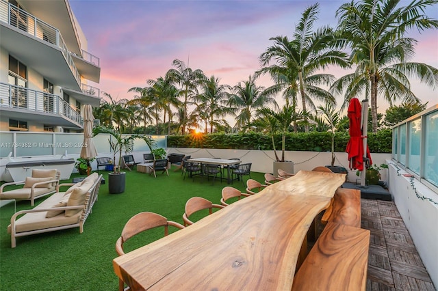 patio terrace at dusk featuring a yard