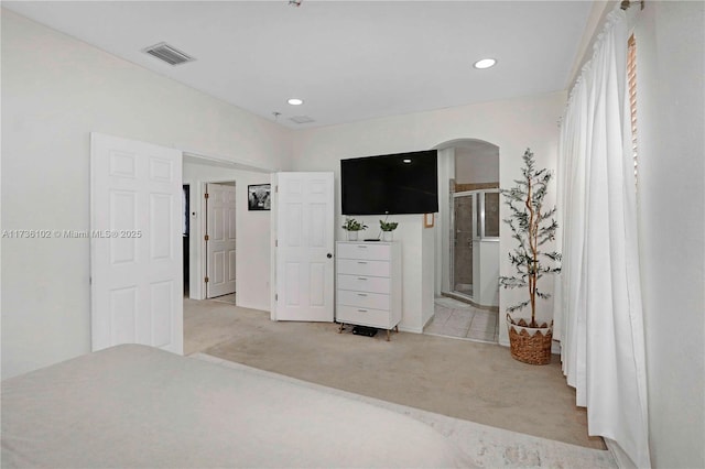 bedroom featuring arched walkways, connected bathroom, recessed lighting, light colored carpet, and visible vents